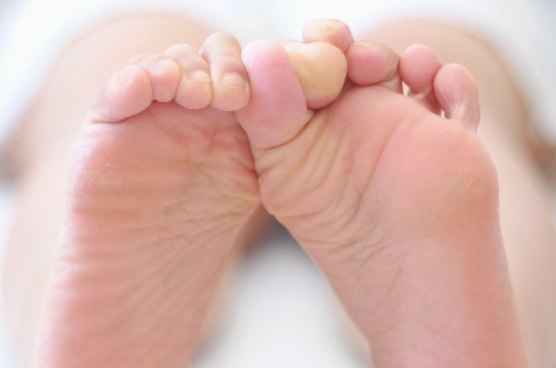 A woman is rubbing her feet together as a way of self-soothing