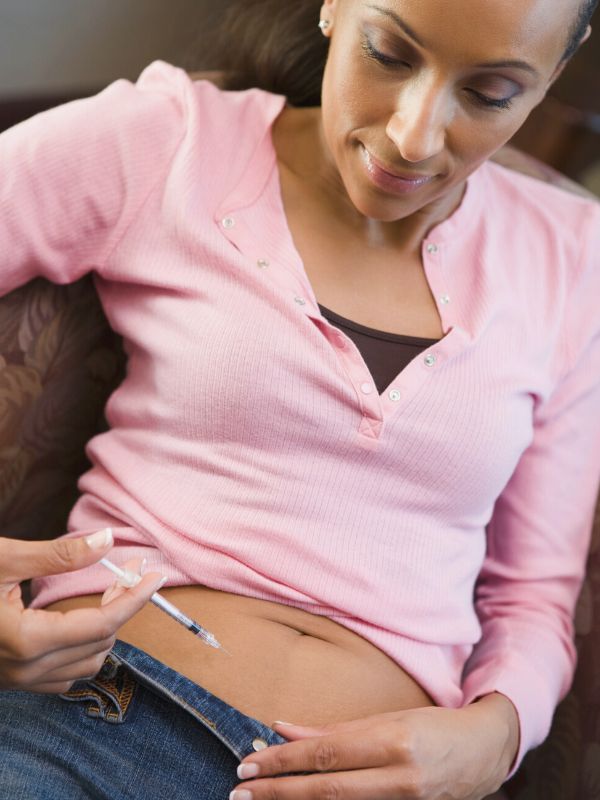 A woman is injecting Progesterone into her lower belly area to help with conceiving a baby
