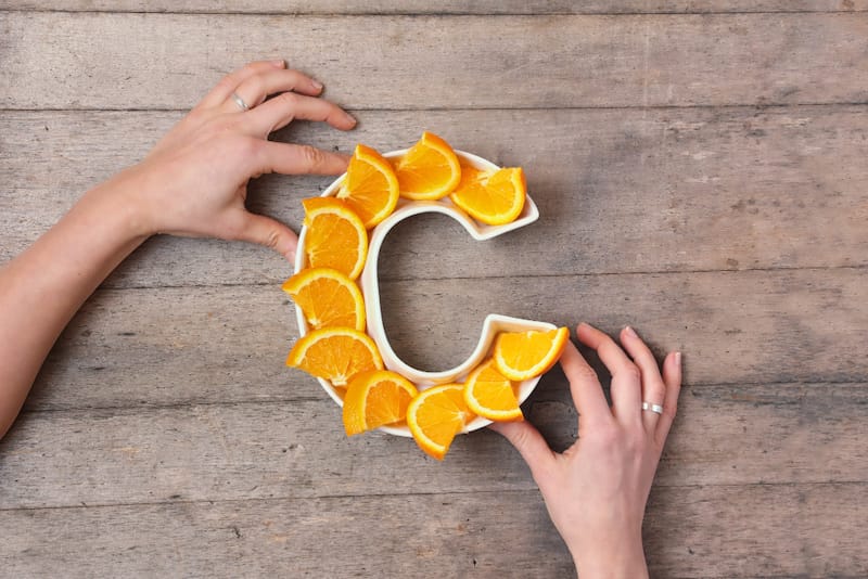 A plate in the shape of a C is filled with sliced oranges, which are high in vitamin C.