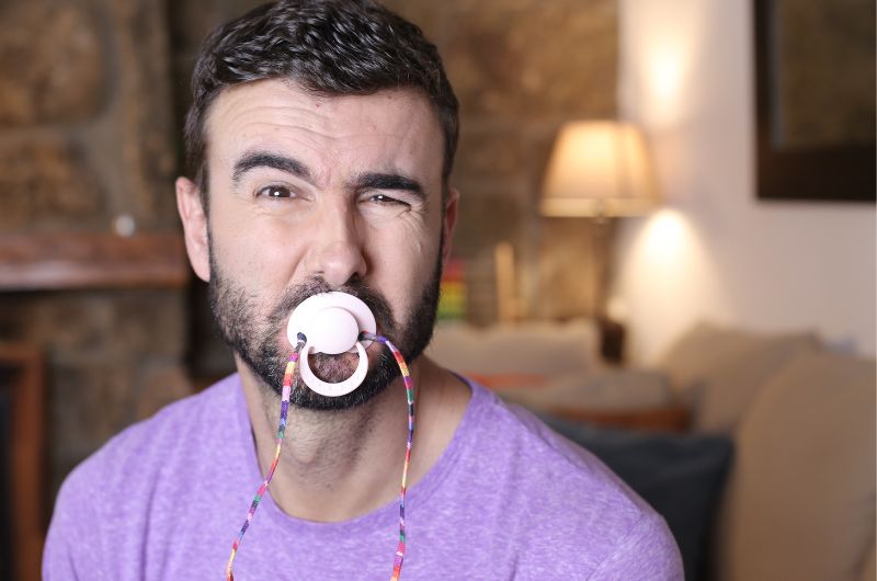 An adult man is using a pacifier for self soothing