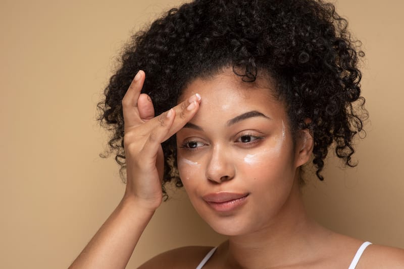 A young woman is using a CBD skincare cream for it's anti inflammatory benefits