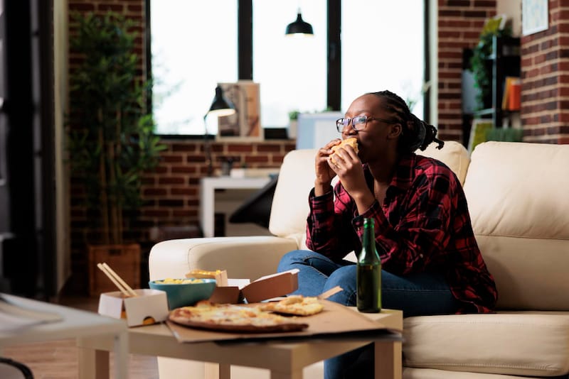 A young woman is eating while she is watching tv.