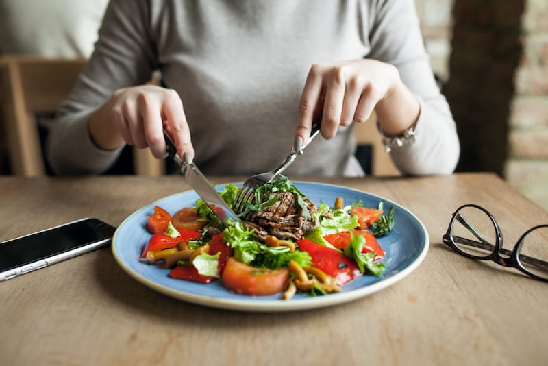 A woman is having a salad during her set daily lunchtime schedule to help her from overeating.