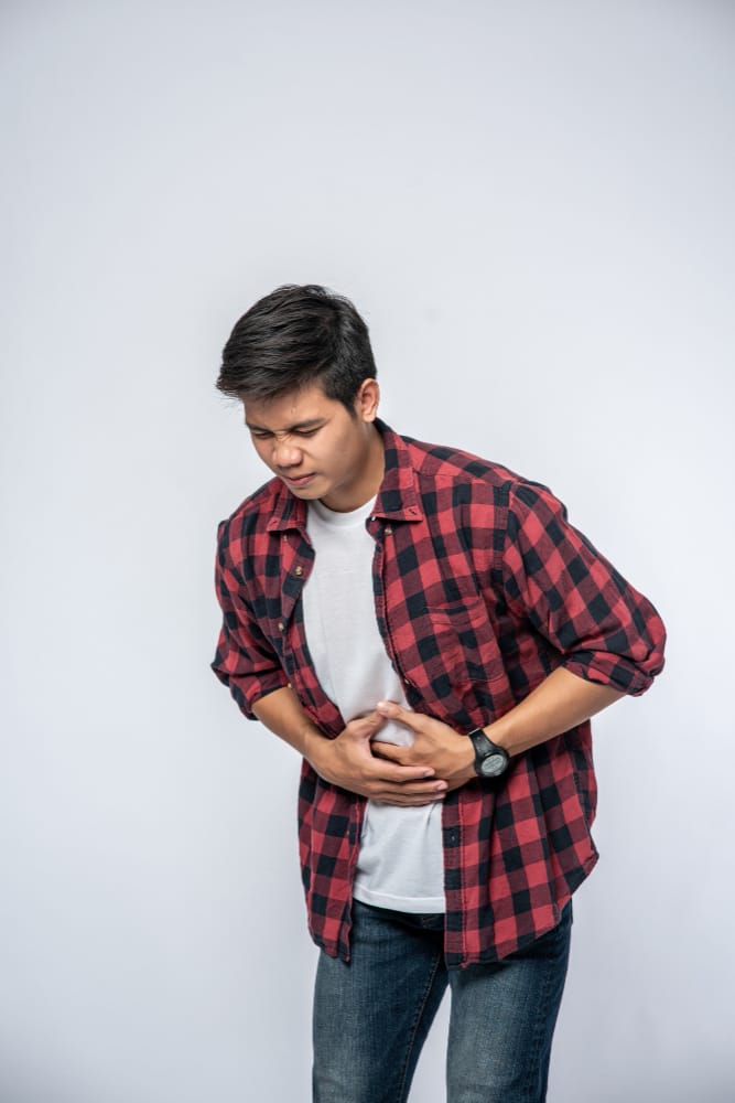 A man is holding his stomach as he is having abdominal pain because of not eating enough fibrous foods
