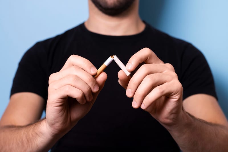A man is shown breaking a cigarette in half