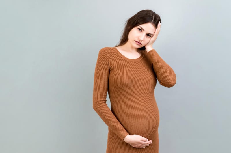A pregnant woman is not feeling too well, she may have food poisoning from something she ate recently.