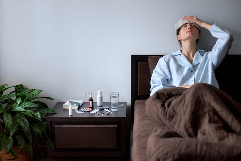 A woman is resting in bed because she has a headache as a result of taking Amlodipine