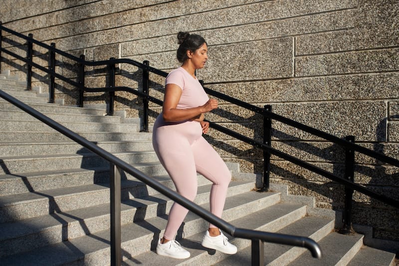 A woman is running up and down outdoor stairs as a form of intense cardio