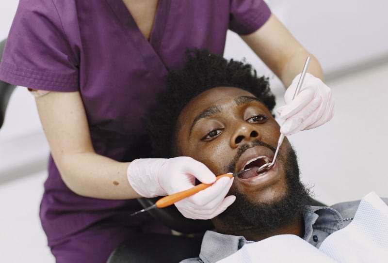 A dentist is checking her patient if stitches are dissolved days after receiving oral surgery