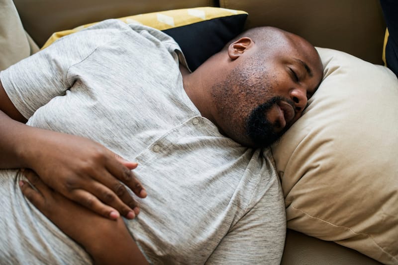 A man with obstructive sleep apnea is trying to sleep comfortably on his back without having his tongue fall back into his throat