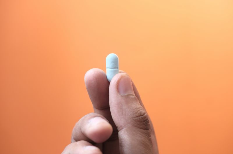 A man is holding an antibiotic tablet