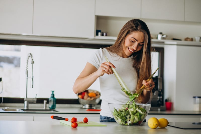 A young woman is preparing a salad in her kitchen