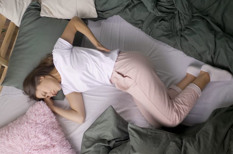 A woman is having lower back pain after being in a poor sleeping posture all night