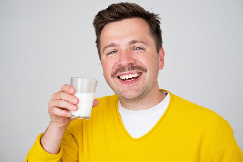 A man is happy as he is drinking a glass of milk