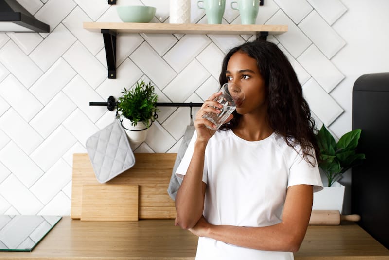 A young woman is drinking water to help with her digestion
