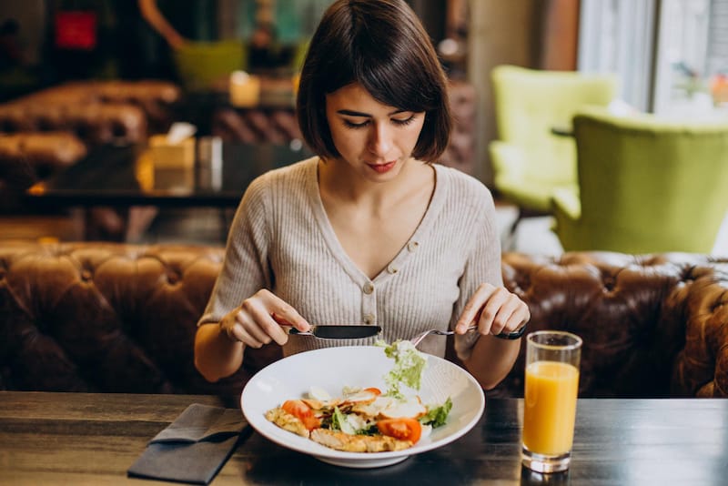 A woman is eating her meal slowly to help prevent excess gas buildup