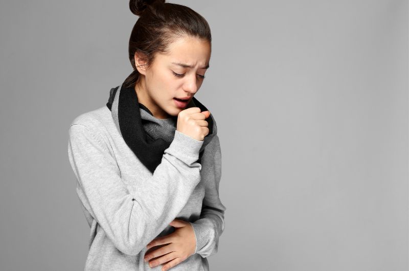 A young woman is coughing a lot as a result of her bronchitis