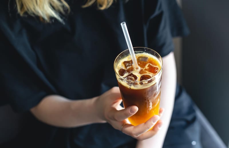 A woman is holding a cup of iced coffee that she made at home
