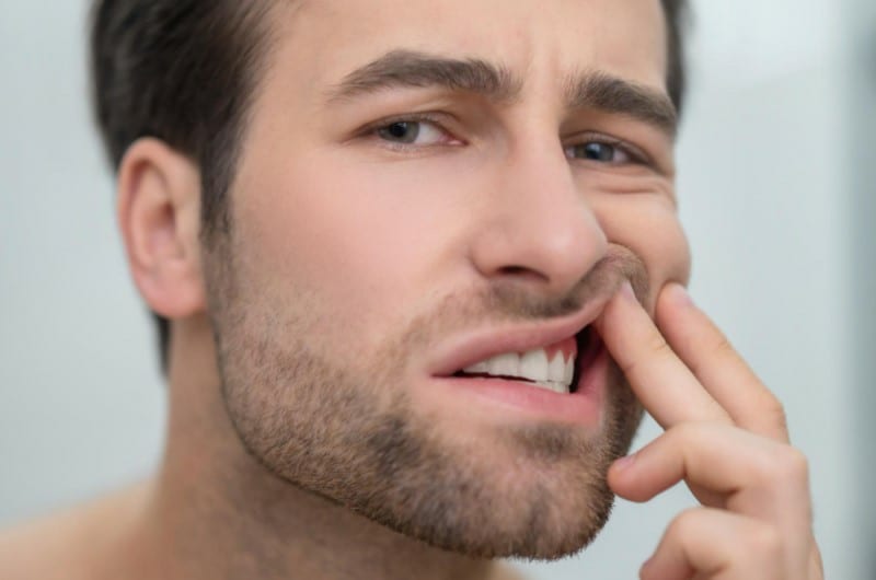 A man is checking his teeth to see if oil pulling had any benefits to his oral hygiene. 