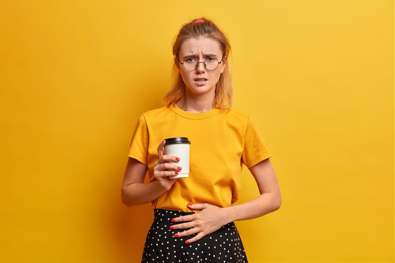 A woman with IBS is not feeling so well after drinking coffee