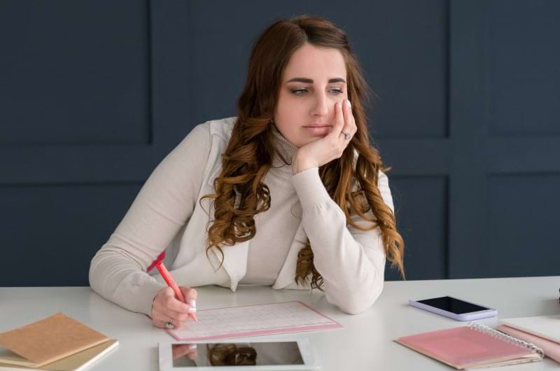 A young woman is sitting at a work desk, losing focus due to anxiety.