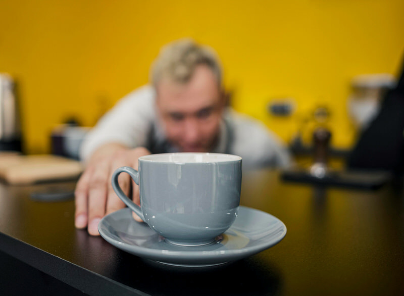 A man is observing a cup of coffee that's on his desk