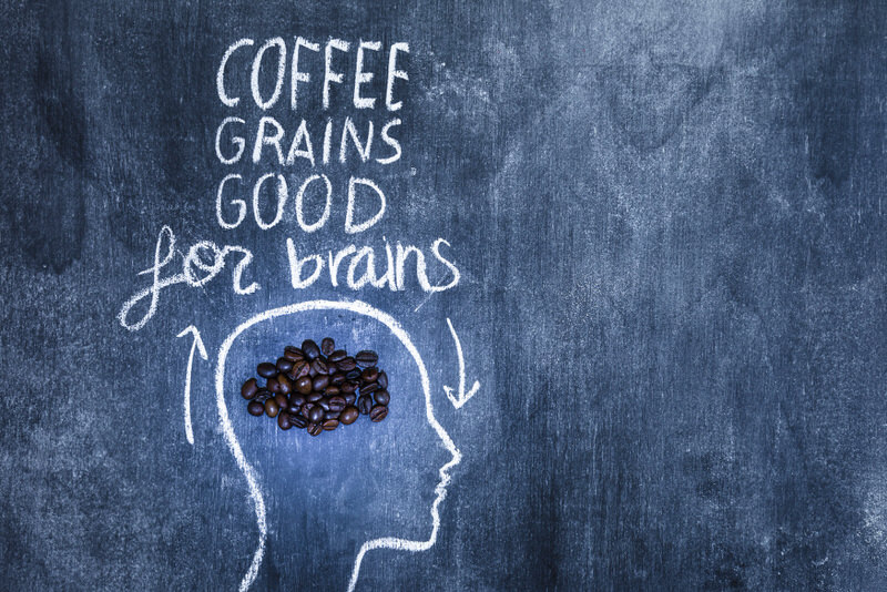 A chalk drawing of a head with coffee grounds by the brain, with a statement saying "coffee grains good for brains"