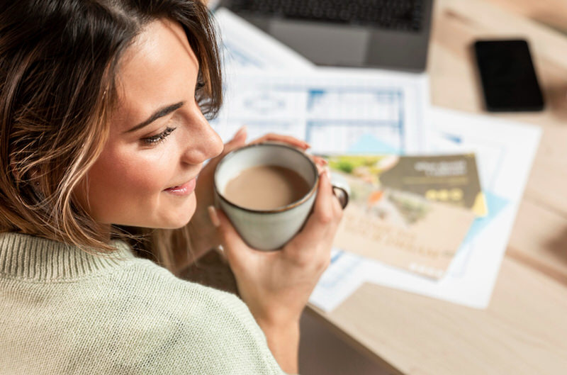 A woman is happily drinking coffee as she starts her morning workday