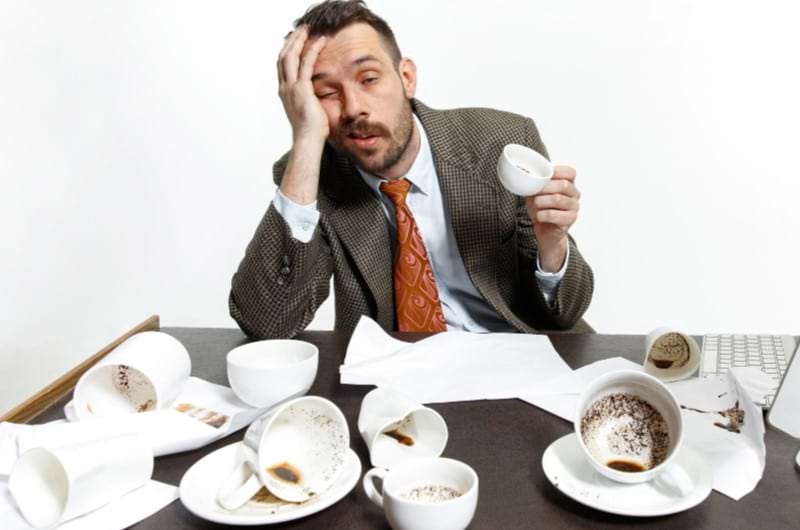 An office worker has had multiple cups of coffee but still feels sleepy which could signal a high caffeine tolerance.