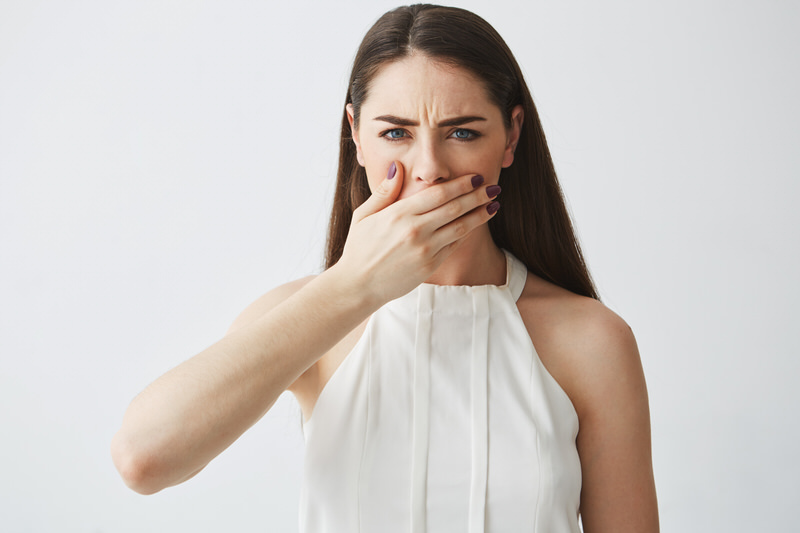 A young pregnant woman is covering her mouth as she noticed she has bad breath