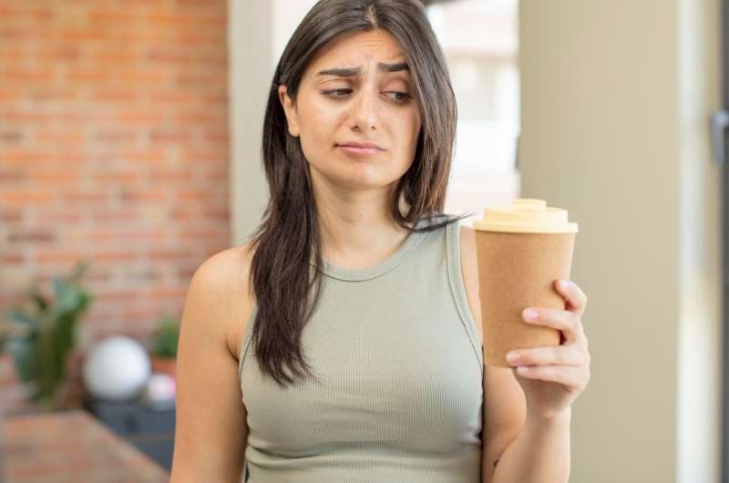 Woman holding a coffee is wondering how to manage her coffee tolerance