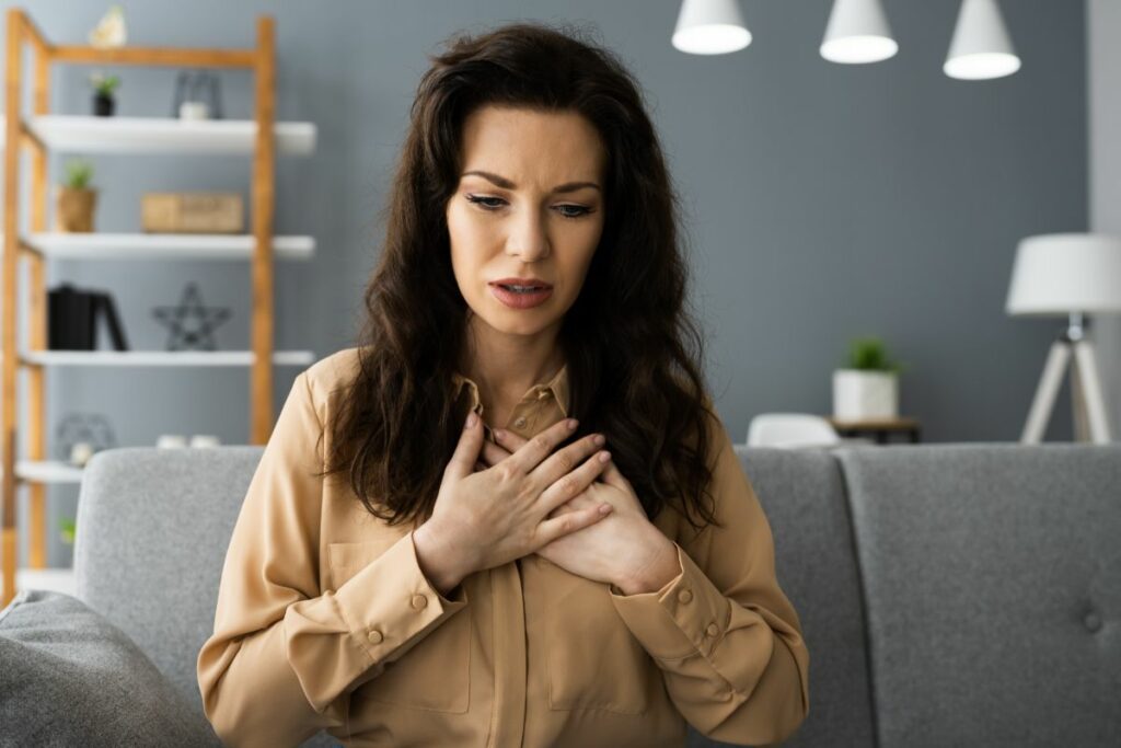 A woman is clenching her chest as she's feeling a chest cold coming