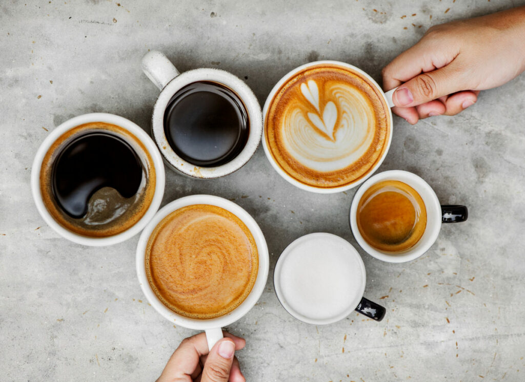 A variety of coffee cups are shown, some black, and some have creamer and cinnamon powder