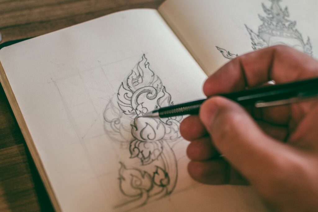 A person is sketching a design in his sketchbook