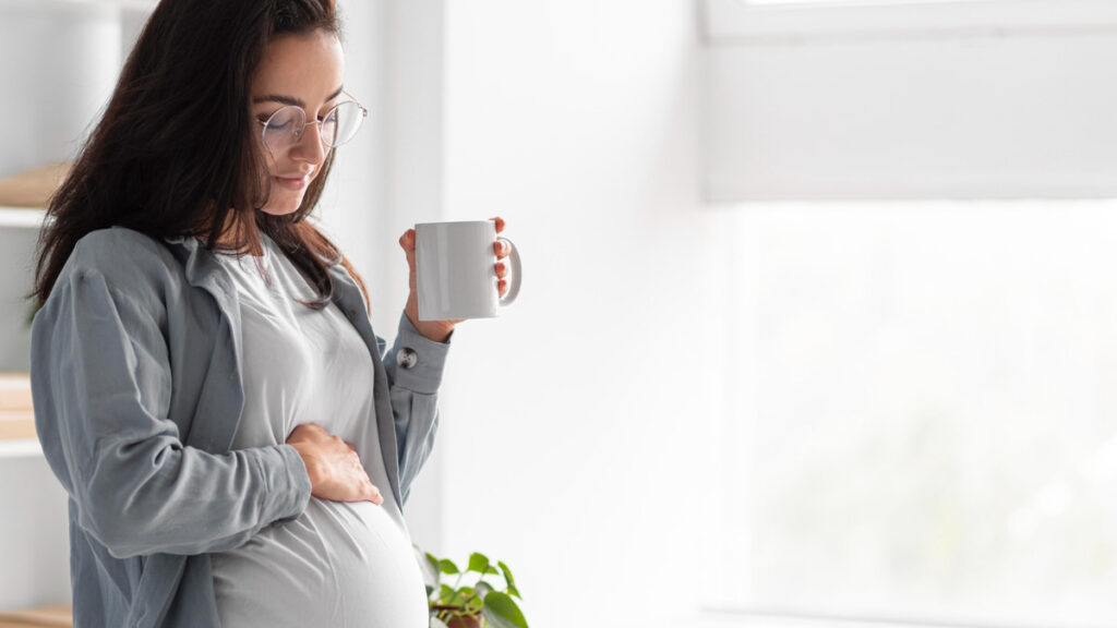 A pregnant woman is enjoying her coffee