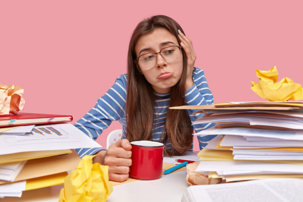 A college student is drinking too much coffee while studying, and is feeling the side effects.