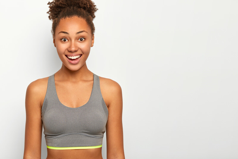 A young woman is trying on different sports bras to find the best fit for her.
