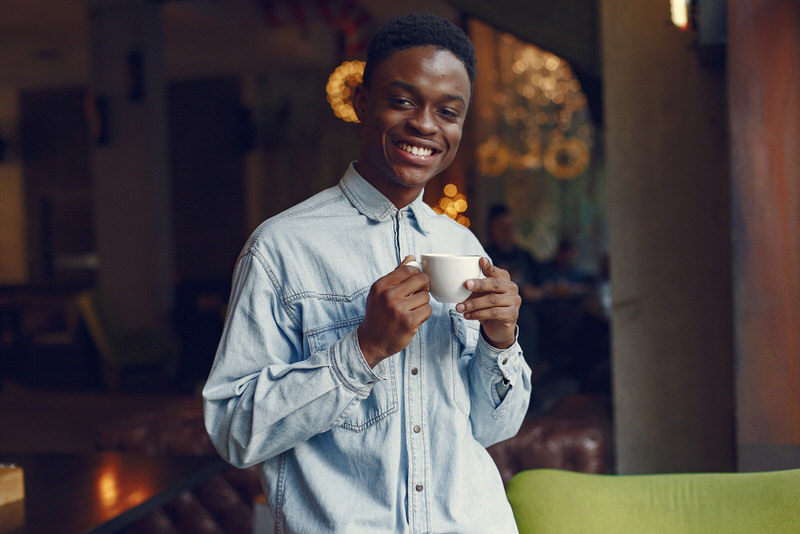 A young man is drinking green tea to help stimulate his metabolism and burn calories.