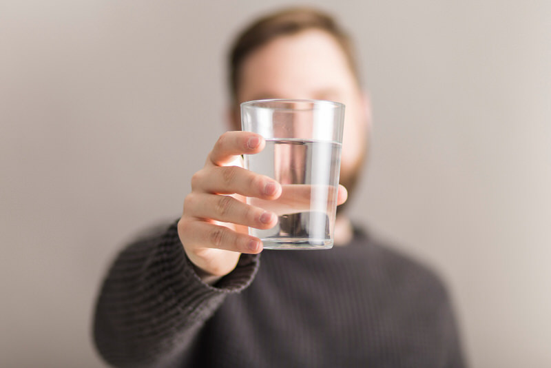 A middle-aged man is drinking lots of water before his upcoming colonoscopy, for an easier exam.