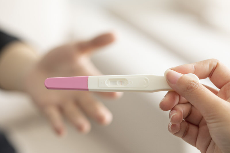 A young woman is holding a pregnancy test after completing it.