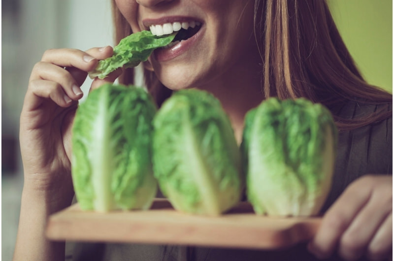 A young woman is eating some Chinese cabbage, a healthy vegetable.