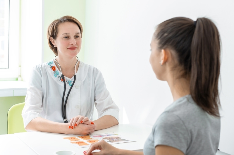 A young woman is talking to her doctor during her regular checkup.