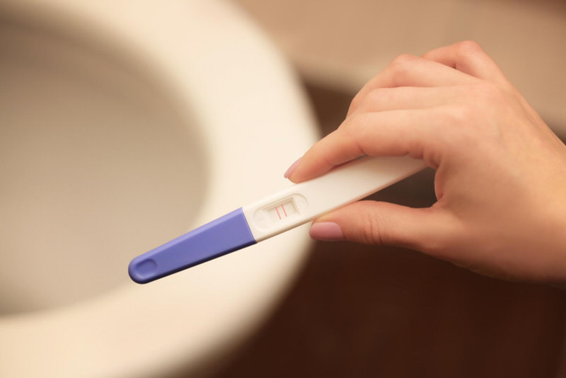 A young woman is about to take a pregnancy test in the bathroom.