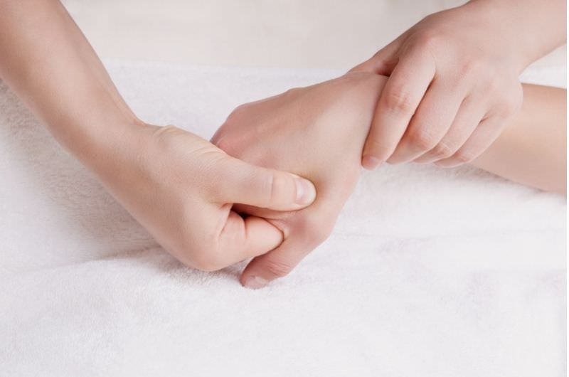 A woman is getting acupressure done on her hand to help with her period cramps pain.