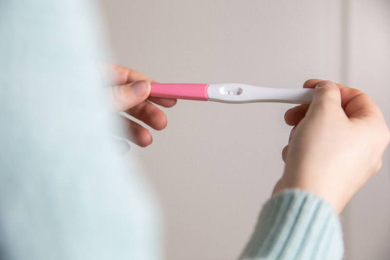 A young woman is looking for evaporation lines on a pregnancy test she recently took at home.