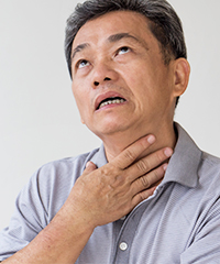 A man holding his throat because of pain and discomfort from his acid reflux
