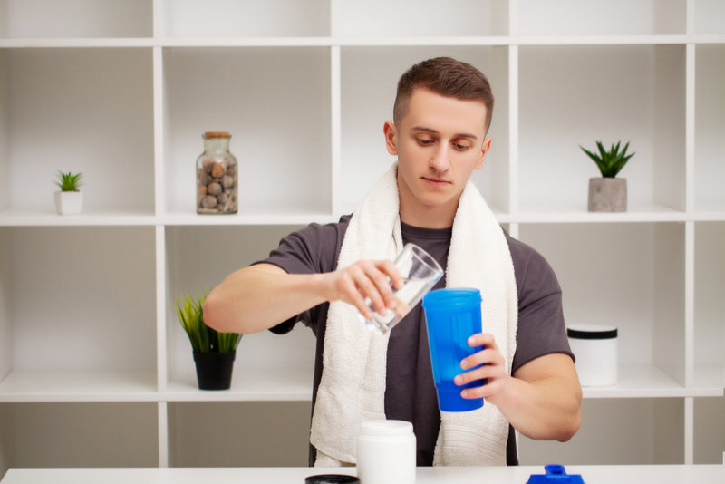 A young man is preparing a creatine and protein powder shake on his non-workout day.