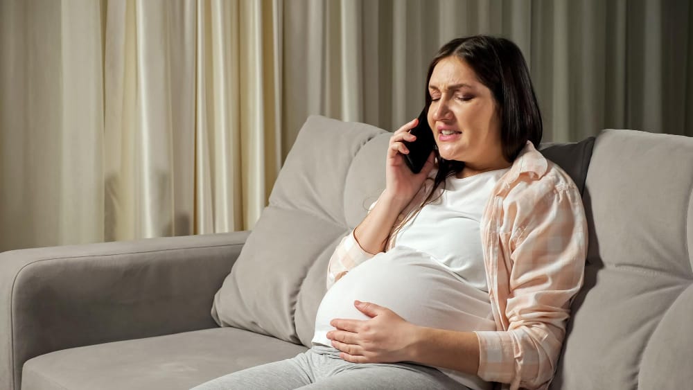 A pregnant woman in her last trimester is on the phone with her OB-GYN, concerned because she feels a lot of pain when standing up but not sitting down