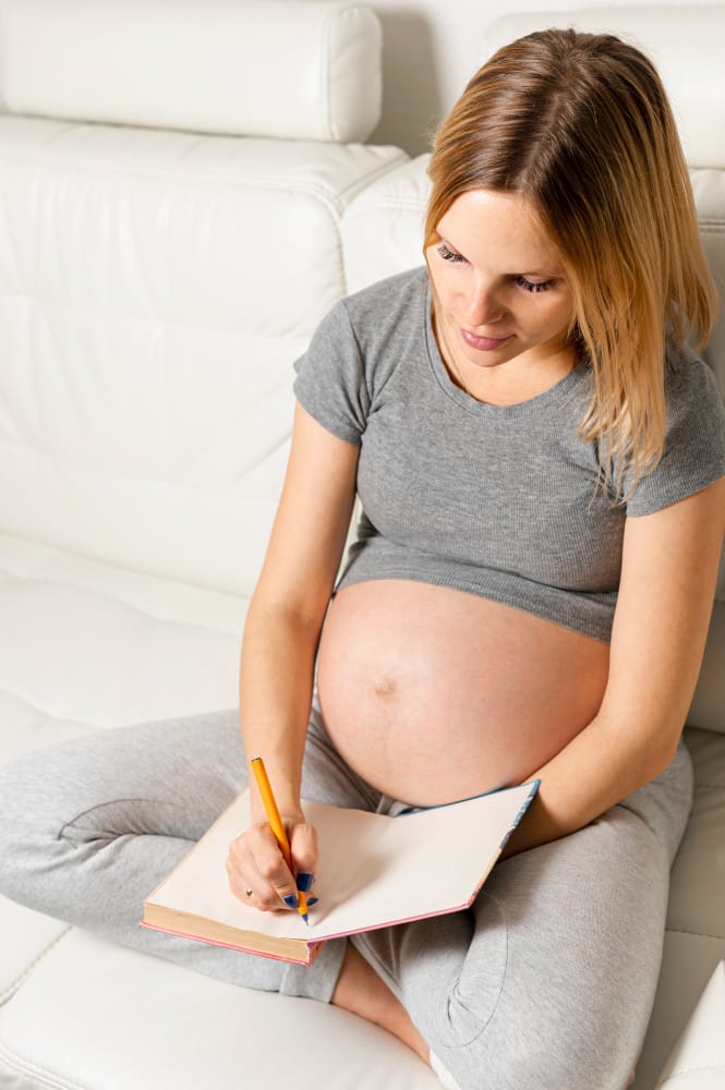 A pregnant woman is journaling her day and her daily blood sugar level to monitor her gestational diabates
