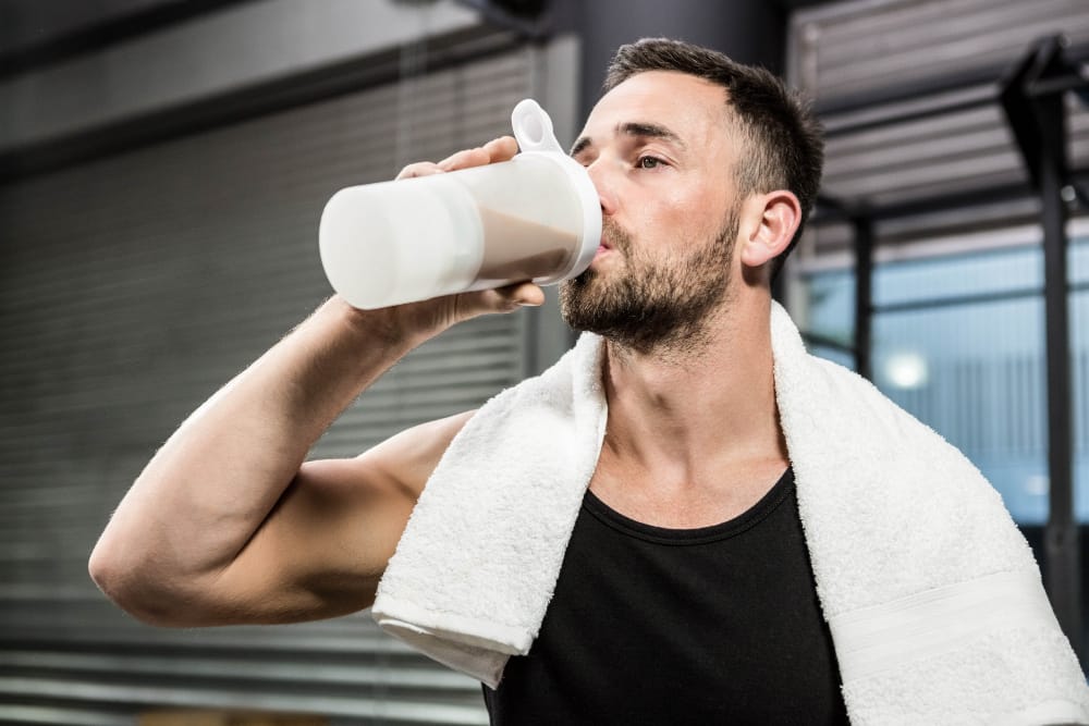 A man is drinking a protein shake after his workout to improve his muscle recovery and growth